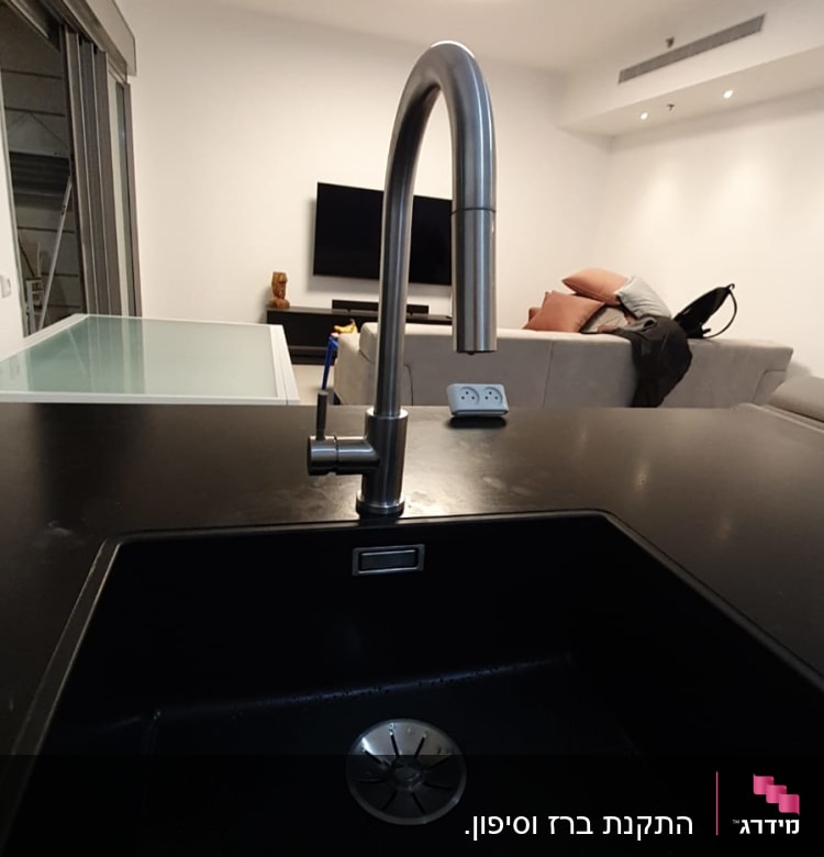 ברז נירוסטה מעל כיור שחור במטבח מודרני